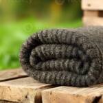 Dark charcoal rolled chunky wool blanket on wooden pallet