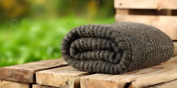 Dark charcoal rolled chunky wool blanket on wooden pallet