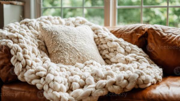 Cream chunky knit blanket draped on brown leather sofa