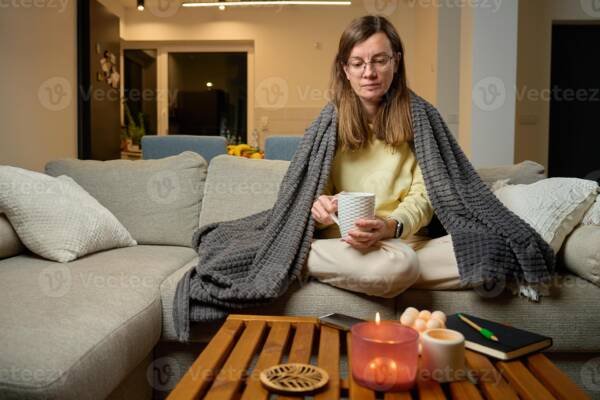 Woman wrapped in cozy chunky knit blanket holding warm mug